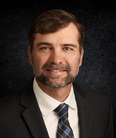 a man wearing a suit and tie smiling at the camera