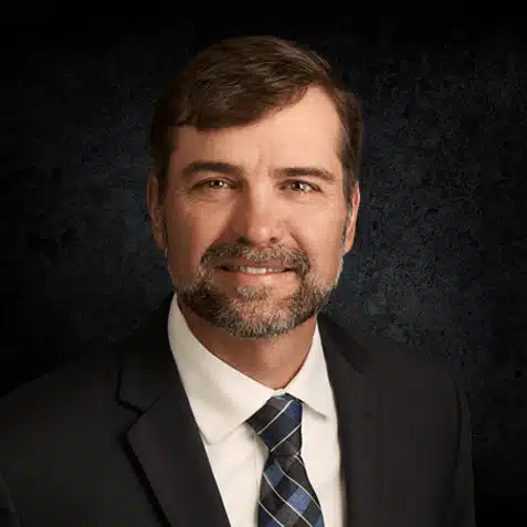 a man wearing a suit and tie smiling at the camera